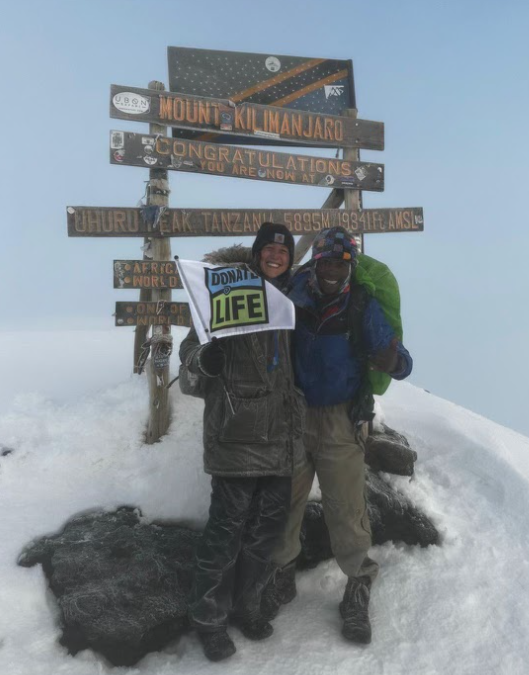 Picture of two people holding Donate Life Flag on top of Mount Kilimanjaro